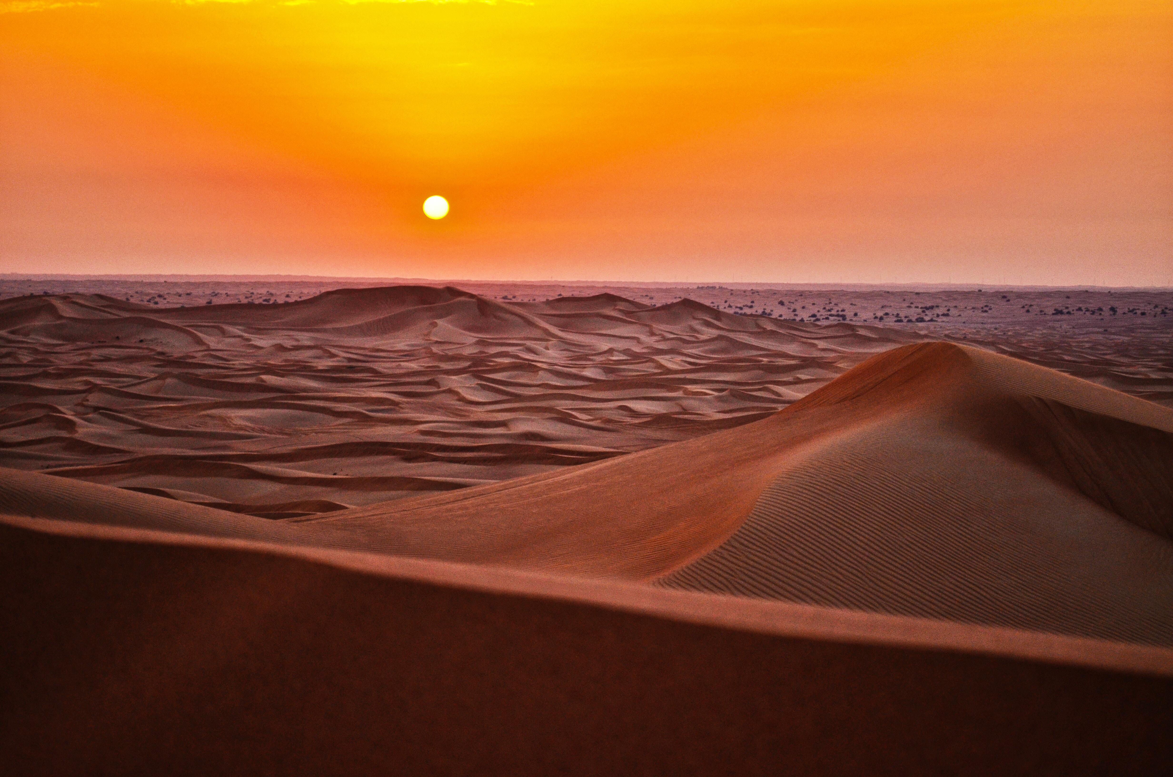 sandy desert at sunset with orange sky